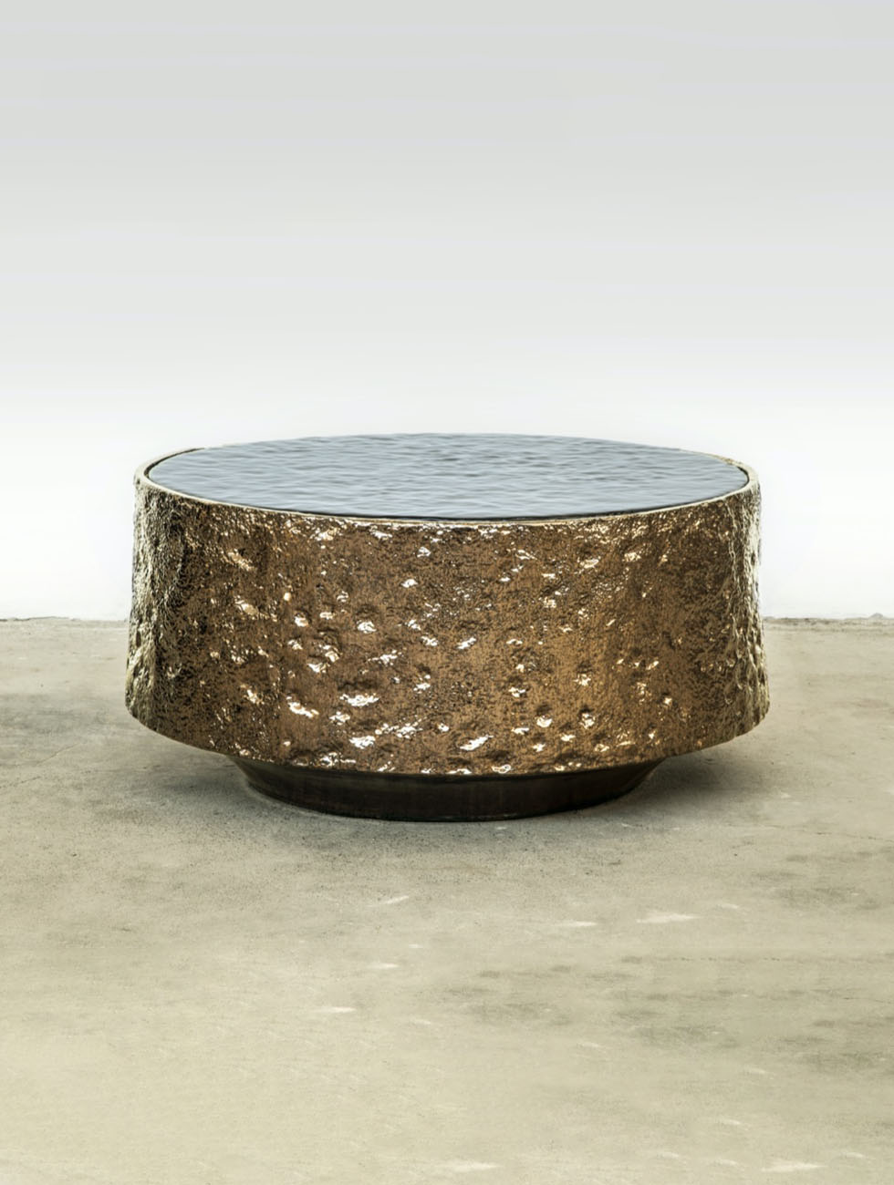 Tavolino di design Mola progettato da Doodesign: base artigianale in terracotta smaltata bronzo e top in vetro fuso ricco di bolle d'aria.